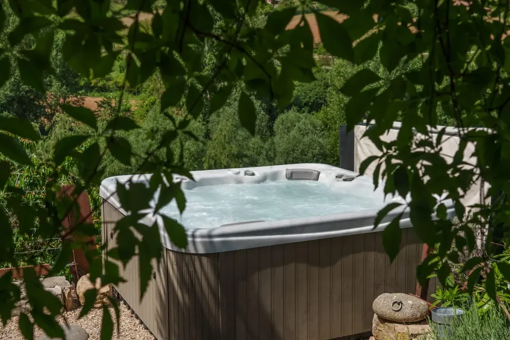 Jacuzzi privatif niché sous la végétation du gîte spa