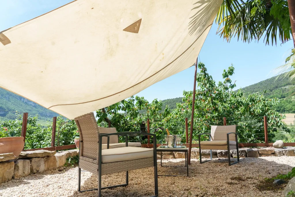 Terrasse avec voile d'ombrage et salon de jardin du gîte spa