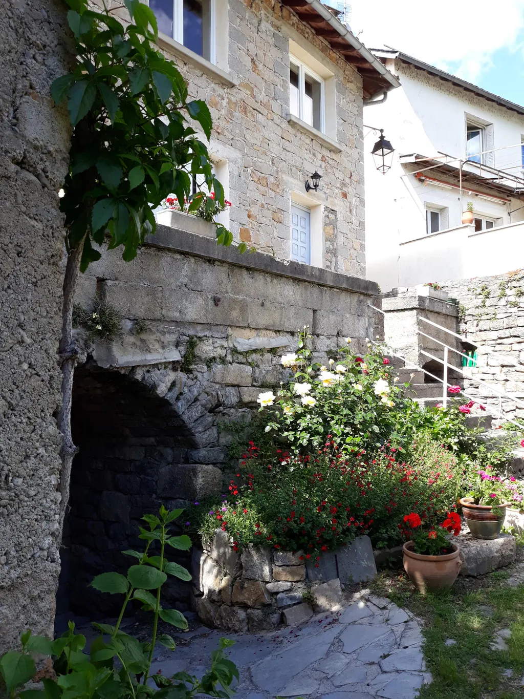 Ruelle en pierre fleurie de roses au pied du gîte Gorge du Tarn