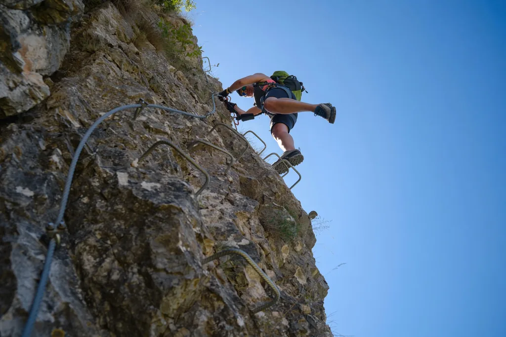 Grimpeur sur la via ferrata d'une falaise des Grands Causses